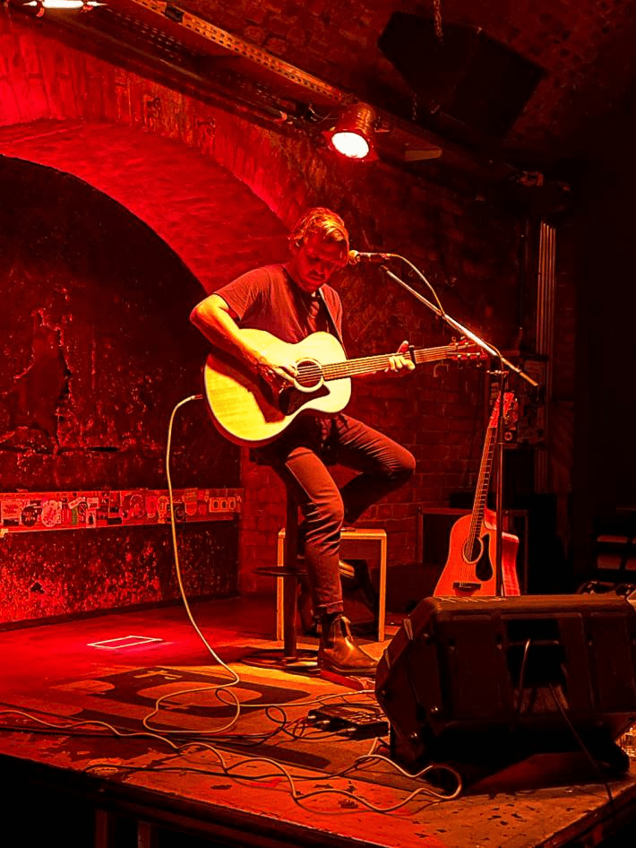 A musician singing and playing the guitar during a concert.