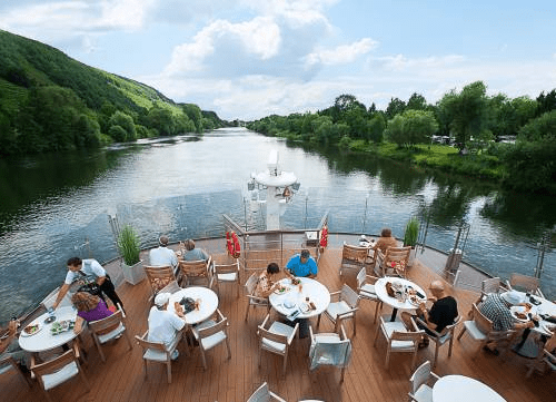 People sitting at tables with a beautiful view on the river during the Viking Ve River Cruise.