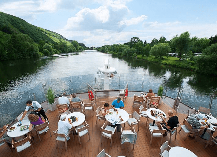 People sitting at tables with a beautiful view on the river during the Viking Ve River Cruise.