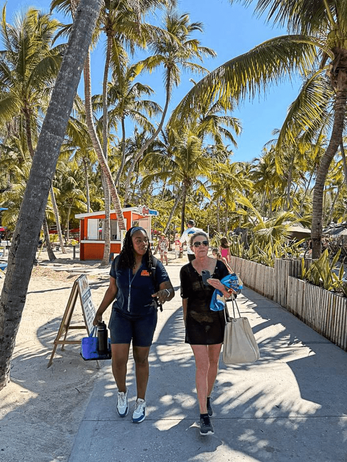 Two women walking on a path surrounded by palm trees.